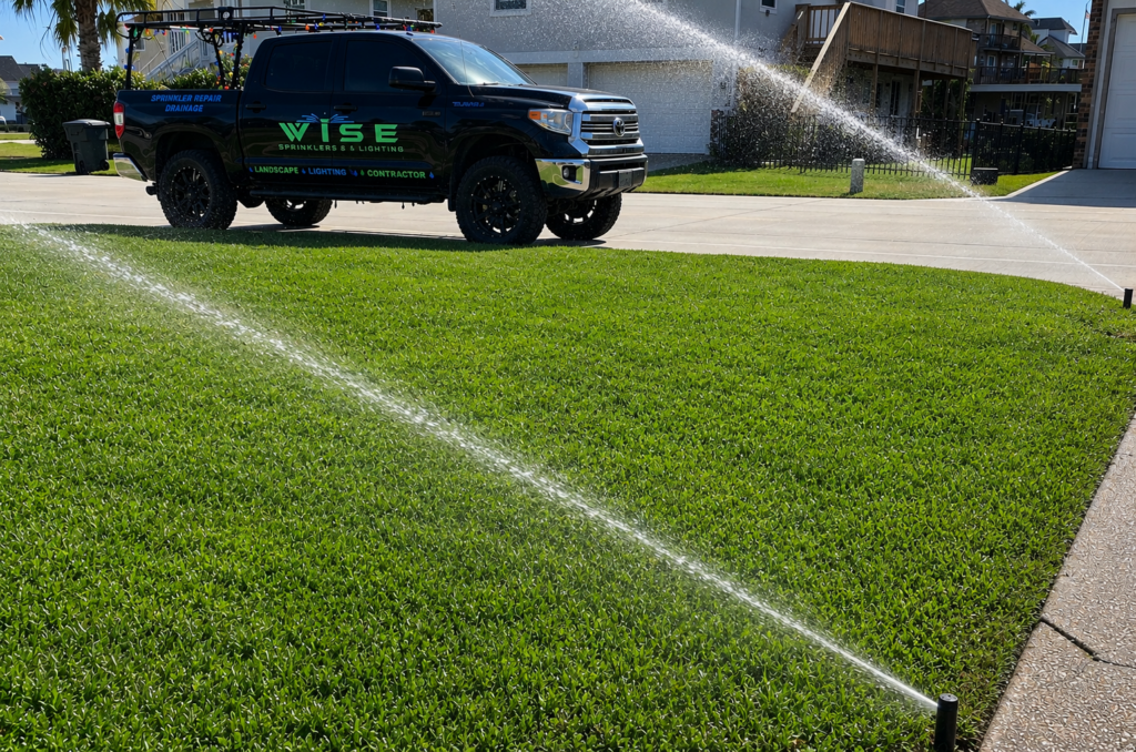 Wise Sprinklers & Lighting truck servicing a residential irrigation system with sprinkler heads watering a healthy green lawn.