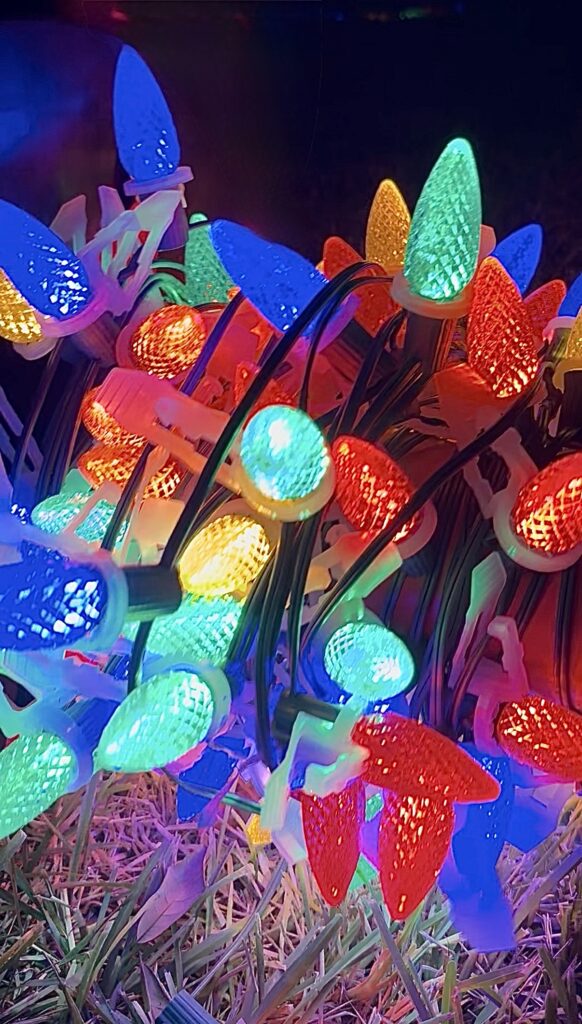 Close-up of colorful custom C9 LED Christmas lights ready for professional roofline installation, featuring vibrant red, green, blue, and warm white bulbs.